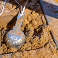 A round light fixture between attic joist cavities, partially covered with older insulation.