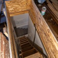 A worker secures strips of oriented strand board around an attic access opening. 