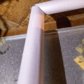 Two white pieces of pipe wrap are cut at a 45 degree angle.