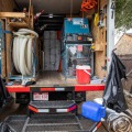 The back of a well-organized truck with an insulation blowing machine and hoes. 
