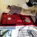 A worker installing a red door shroud in the black blower door frame.