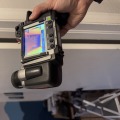 Black thermal imaging camera with a screen showing different colors