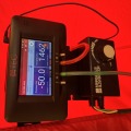 A digital display with blue boxes and white lettering on a black meter device with green and red tubing. 