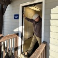 A worker placing a black blower door frame in a white door frame.