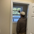 A worker closing the white frame of a window.
