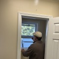 A worker opening the white frame of a window.